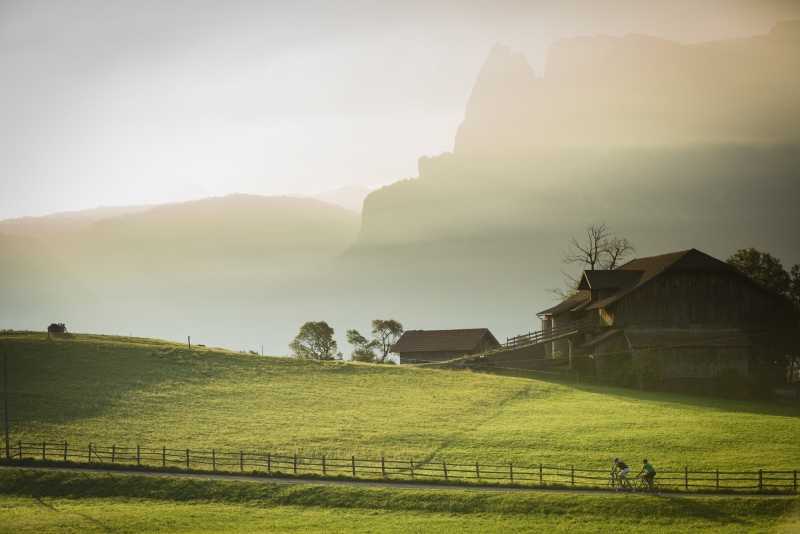 Due ciclisti in un paesaggio dolomitico illuminato da una calda luce dorata Bike Tour Evolution
