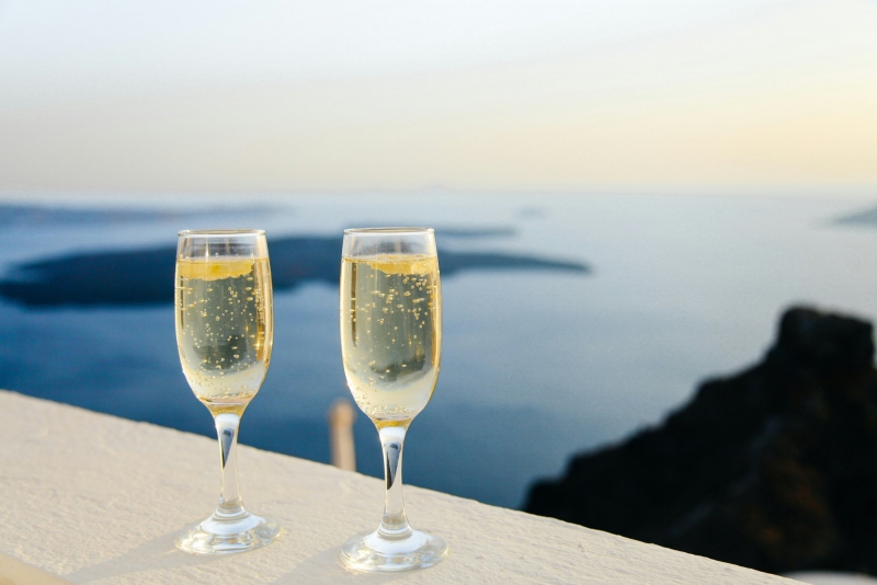 Due flute di champagne appoggiati su un muretto con vista mare al tramonto Bike Tour Evolution