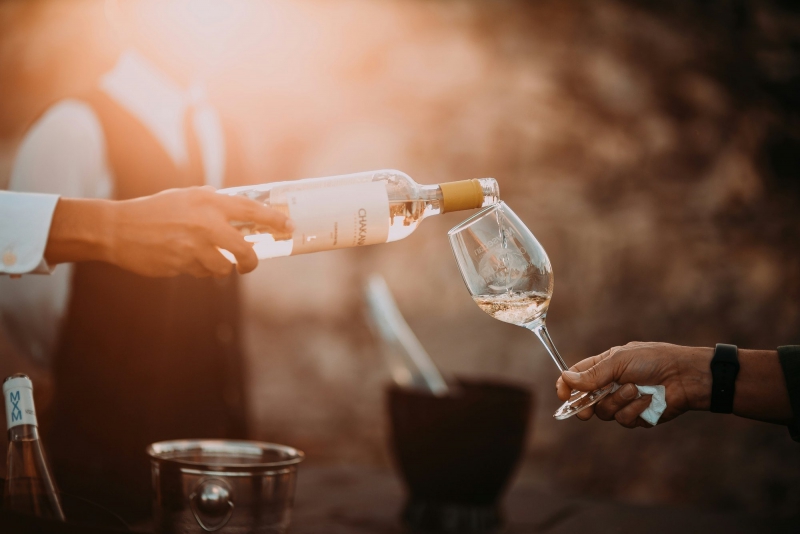 Una persona versa un bicchiere di vino bianco a una donna durante una raffinata esperienza di degustazione Bike Tour Evolution