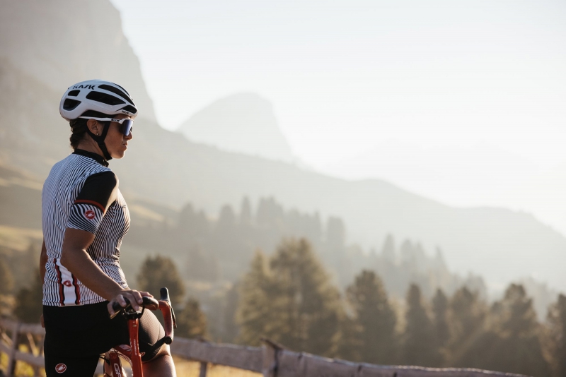 Primo piano di un ciclista in pausa con sguardo concentrato, casco e abbigliamento tecnico, immerso nella bellezza naturale delle Dolomiti Bike Tour Evolution