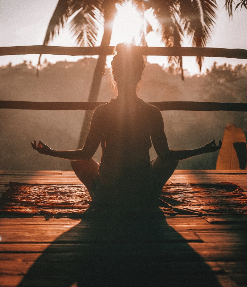Donna che pratica yoga in posizione di meditazione al tramonto in un ambiente naturale e tranquillo Bike Tour Evolution