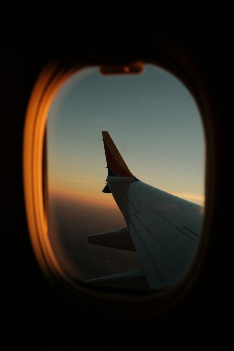 Vista del tramonto dal finestrino di un aereo, con il cielo colorato sopra le nuvole Bike Tour Evolution