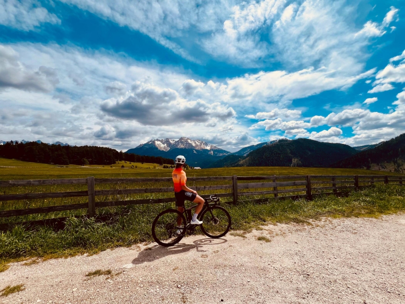 Ciclista con maglia Bike Tour Evolution fermo a bordo strada, mentre ammira le montagne in lontananza Bike Tour Evolution